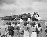 福岡県の飯塚から二日市に向け、筑豊本線を走る昭和天皇を乗せたお召し列車と奉迎者たち。牽引機はＣ１１の重連。手前の女性たちは日の丸の小旗を振っているが、東京裁判の終結もあり１９４９年１月１日の連合国最高