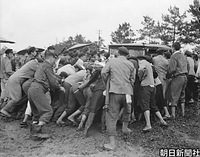 ２３日、佐賀県杵島郡白石町の県立佐賀農業高校で、ぬかるみにはまった昭和天皇の御料車を押し上げる人たち。長靴の人もいるが、多くは素足に下駄で、泥まみれになっている