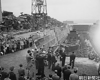 長崎県佐世保市の佐世保船舶工業（現・佐世保重工業）を訪問、ドックを視察される昭和天皇。左は解体された旧海軍艦艇のスクラップの山