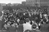 ３月１３日、香川県の高松市役所を訪問した後、同市の奉迎場・中央グラウンドに歩いて向かう際、歓迎に集まった人たちに帽子を振って応えられる昭和天皇。右後ろは三谷隆信侍従長