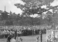 １８日、奈良市・添上郡奉迎場の奈良学芸大学（現・奈良教育大学）前広場で、式台から万歳に帽子を振って応える昭和天皇。左には興福寺五重塔が見える